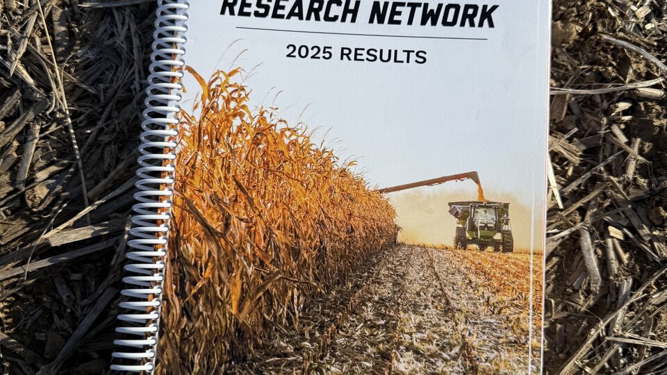 Notebook cover with cornfield and harvesting equipment, lying on dry soil.